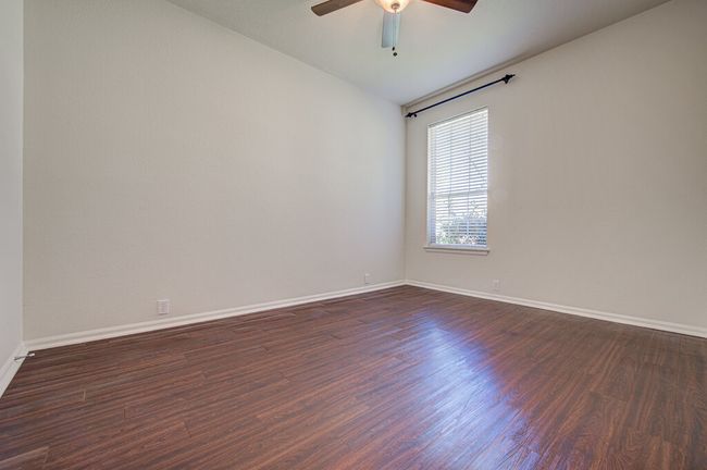 Empty room with a ceiling fan, dark wood-style flooring, and baseboards | Image 26