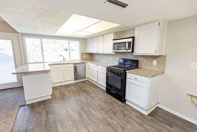 Kitchen featuring dark wood-style floors, visible vents, backsplash, and stainless steel appliances | Image 7