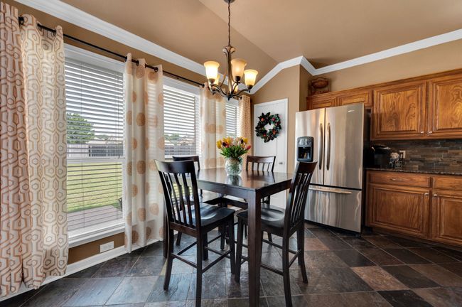 Dining area featuring lofted ceiling, a chandelier, ornamental molding, and stone tile floors | Image 17