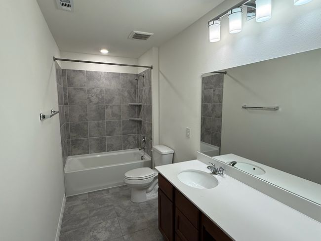 Bathroom featuring toilet, vanity, bathtub / shower combination, and baseboards | Image 18