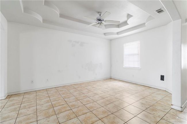 Unfurnished room with a tray ceiling, a ceiling fan, and light tile patterned floors | Image 5