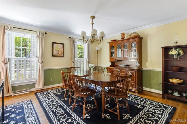 Dining room featuring a chandelier, healthy amount of natural light, wood finished floors, and crown molding | Image 8
