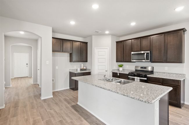 Kitchen with a sink, arched walkways, visible vents, dark brown cabinets, and appliances with stainless steel finishes | Image 6