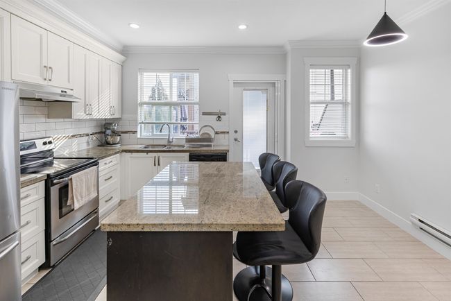 Kitchen with appliances with stainless steel finishes, crown molding, plenty of natural light, a kitchen breakfast bar, and under cabinet range hood | Image 8