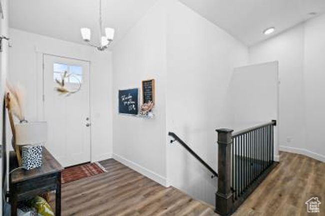 Foyer entrance featuring wood finished floors, lofted ceiling, baseboards, and a notable chandelier | Image 7