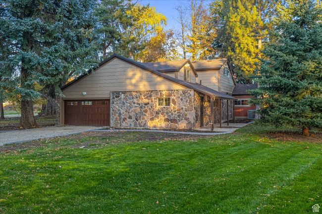 View of home's exterior with a lawn, a garage, asphalt driveway, and stone siding | Image 13