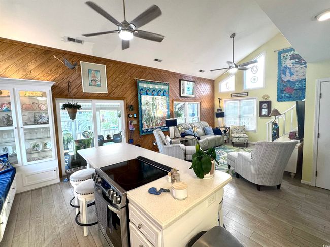 Kitchen with ceiling fan, stainless steel range with electric stovetop, wood walls, light wood-style floors, and white cabinetry | Image 19