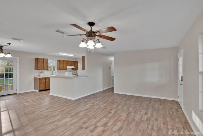 Unfurnished living room featuring sink, light hardwood / wood-style floors, and ceiling fan with notable chandelier | Image 5