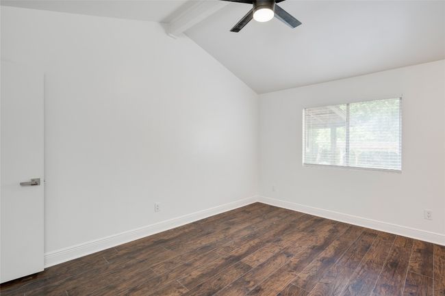 Spare room featuring a ceiling fan, lofted ceiling with beams, dark wood-type flooring, and baseboards | Image 23