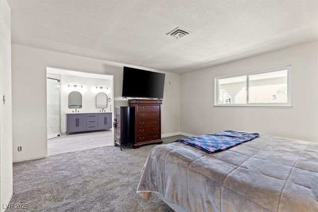 Bedroom with carpet floors, ensuite bathroom, baseboards, visible vents, and a textured ceiling | Image 23