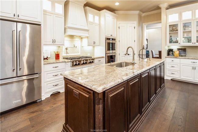 Kitchen featuring appliances with stainless steel finishes, a sink, white cabinets, custom exhaust hood, and dark wood-type flooring | Image 10