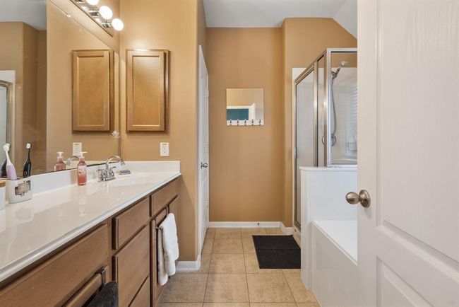 The primary bathroom features tile floors, spacious countertop, walk-in shower, and separate soaking tub. | Image 16