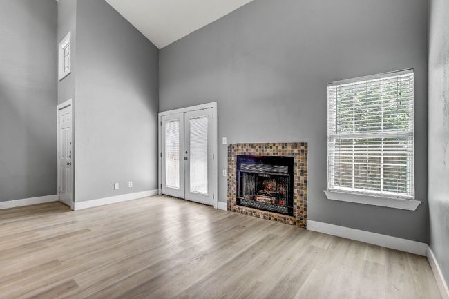Unfurnished living room featuring high vaulted ceiling, wood finished floors, a tile fireplace, and baseboards | Image 5