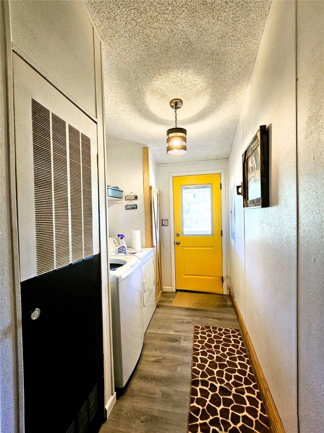 Doorway to outside with separate washer and dryer, wood finished floors, baseboards, a textured ceiling, and a textured wall | Image 14