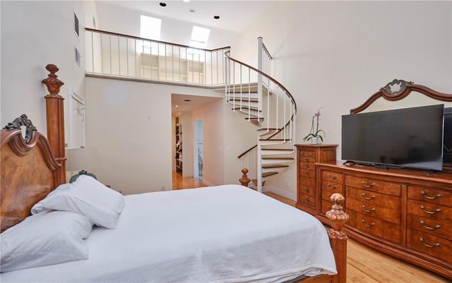 Bedroom with a towering ceiling and light wood-type flooring | Image 26