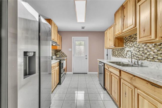 Kitchen with a sink, visible vents, baseboards, decorative backsplash, and appliances with stainless steel finishes | Image 20