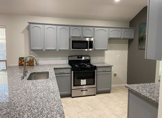 Kitchen featuring gray cabinetry, gas range oven, and light stone counters | Image 10