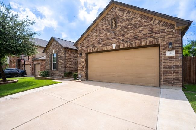 View of front of property with brick siding, concrete driveway, a garage, and a front yard | Image 36