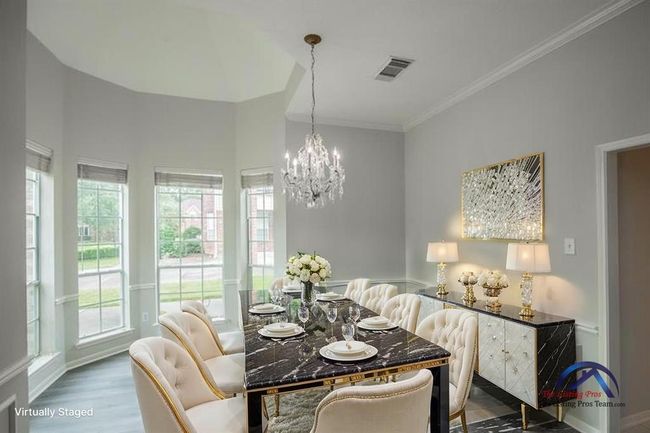 This elegantly virtually staged dining room features a modern chandelier, a large dining table with plush chairs, and abundant natural light from bay windows, creating a bright and inviting atmosphere. | Image 14