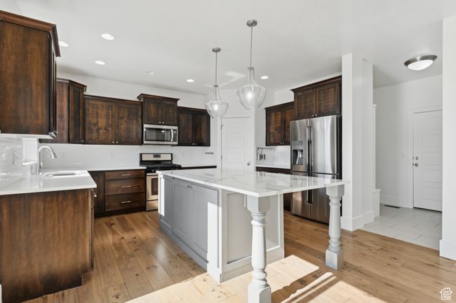 Kitchen with appliances with stainless steel finishes, a kitchen island, decorative backsplash, recessed lighting, and dark brown cabinetry | Image 8