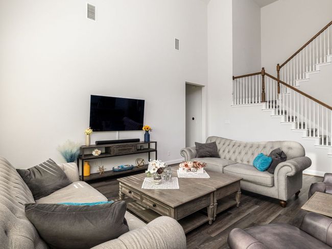 Living room featuring baseboards, visible vents, wood finished floors, and stairway | Image 10