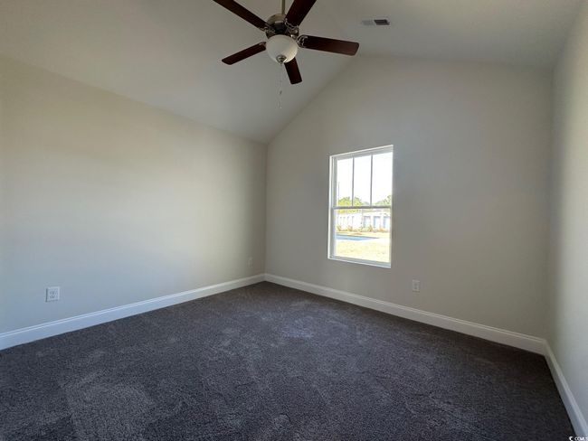 Spare room featuring visible vents, high vaulted ceiling, dark carpet, baseboards, and ceiling fan | Image 12