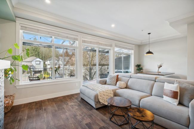 Living area with dark wood-type flooring, baseboards, and a wealth of natural light | Image 5