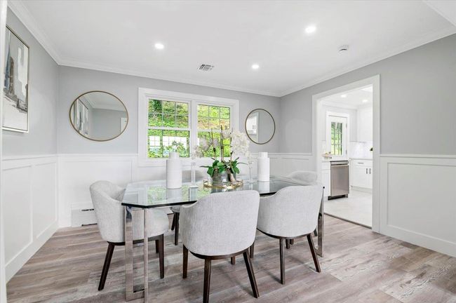 Dining space with wainscoting, crown molding, a decorative wall, light wood-style flooring, and a baseboard heating unit | Image 7
