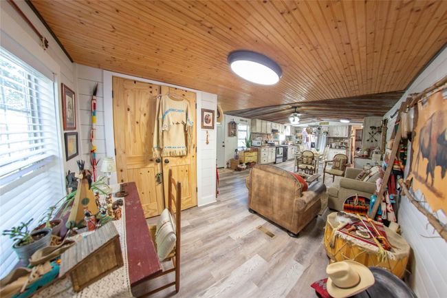 Living room with wood walls, lofted ceiling, wooden ceiling, light hardwood / wood-style flooring, and ceiling fan | Image 17