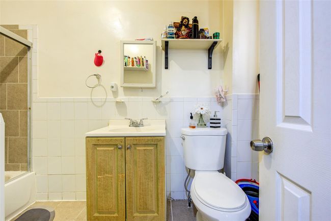 Full bath featuring tile walls, vanity, a wainscoted wall, and shower / bath combination with glass door | Image 22