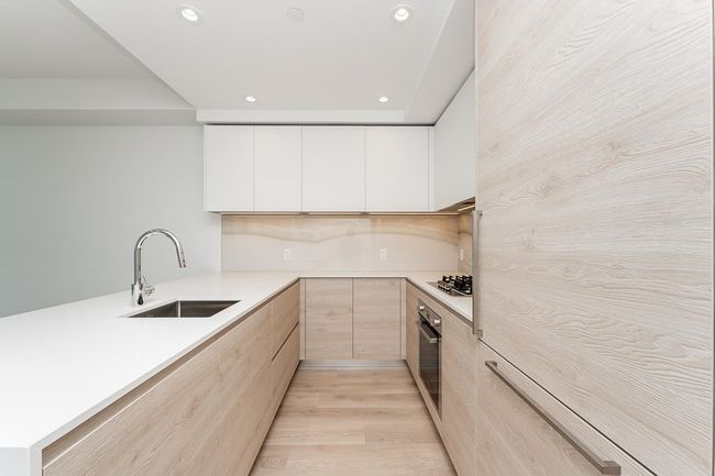 Kitchen with modern cabinets, a peninsula, a sink, stainless steel appliances, and light brown cabinets | Image 8