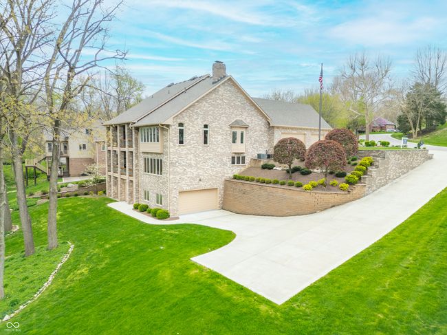 view of home's exterior featuring driveway, stone siding, a chimney, an attached garage, and a yard | Image 8