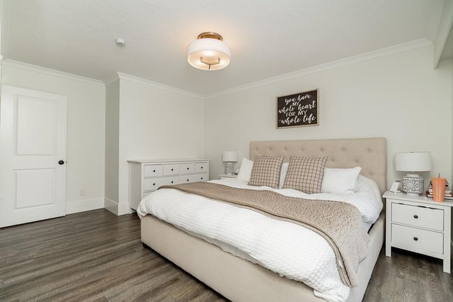 Bedroom with dark wood-type flooring, crown molding, and baseboards | Image 13