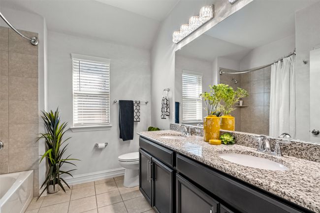 Full bath featuring tile patterned flooring, shower / bath combination with curtain, a sink, and toilet | Image 14