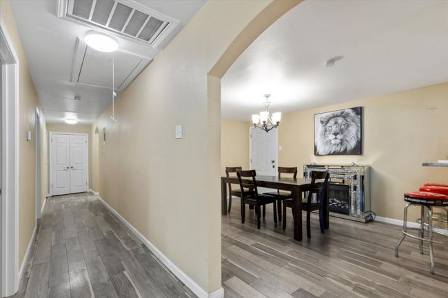Hallway with arched walkways, visible vents, attic access, wood finished floors, and baseboards | Image 7