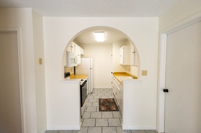 Kitchen with range with electric cooktop, white microwave, a sink, and light countertops | Image 26