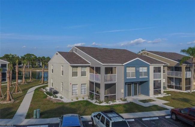 Back of property with a balcony, a yard, a water view, stucco siding, and uncovered parking | Image 33