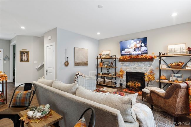 Living area with recessed lighting, wood finished floors, a stone fireplace, and stairway | Image 13