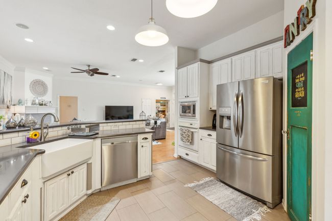 Kitchen with a sink, appliances with stainless steel finishes, dark countertops, ceiling fan, and ornamental molding | Image 13