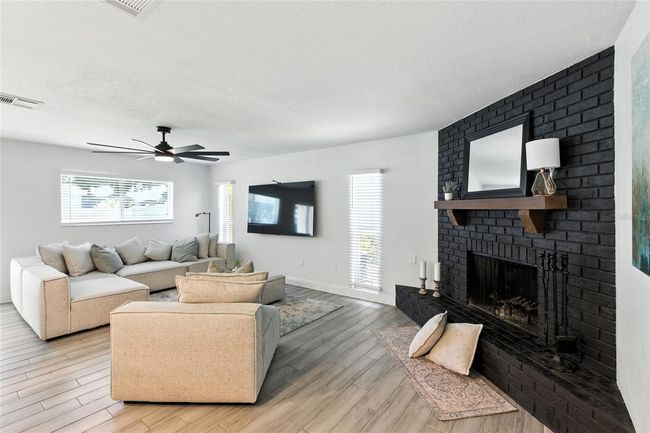 Spacious and inviting living room featuring a true wood-burning fireplace, dramatic black brick surround, and enough space for your biggest sectional and then some | Image 16