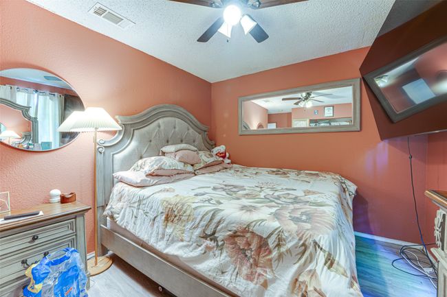 Bedroom featuring baseboards, wood finished floors, visible vents, and a textured ceiling | Image 6