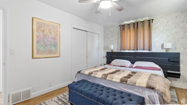 Bedroom with wood finished floors, wallpapered walls, a closet, baseboards, and visible vents | Image 12