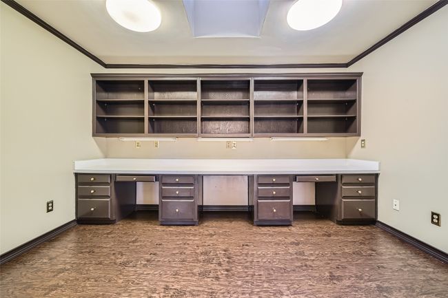 An office with a wall of shelving and desks, . . . | Image 33