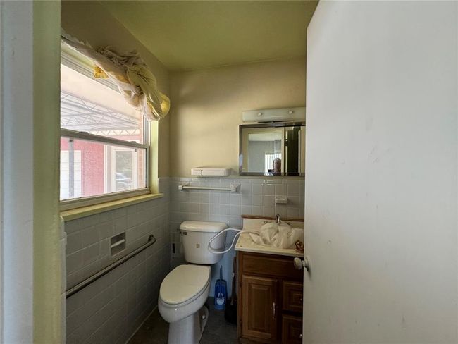 Bathroom with tile walls, vanity, and toilet | Image 35