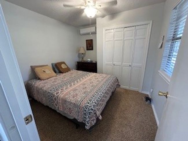 Guest house Bedroom featuring a wall mounted air conditioner, multiple windows, a closet, and carpet | Image 21