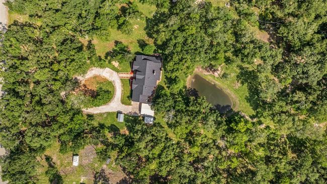 View of the densely wooded Property, with the circular drive and the backyard pond. | Image 44