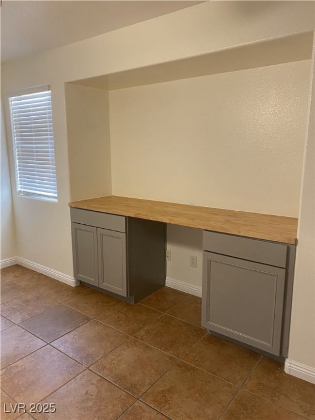 Unfurnished office featuring dark tile patterned flooring, built in study area, and baseboards | Image 21