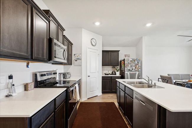 Kitchen with appliances with stainless steel finishes, light countertops, an island with sink, dark brown cabinetry, and recessed lighting | Image 5