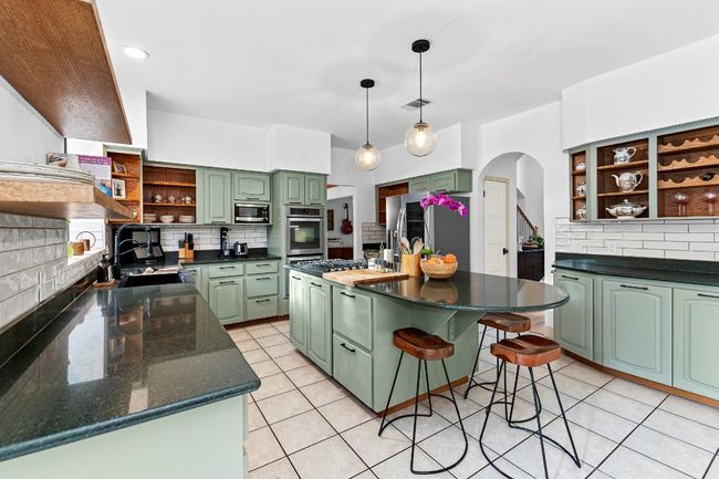 Kitchen with open shelves, green cabinetry, arched walkways, and tasteful backsplash | Image 12