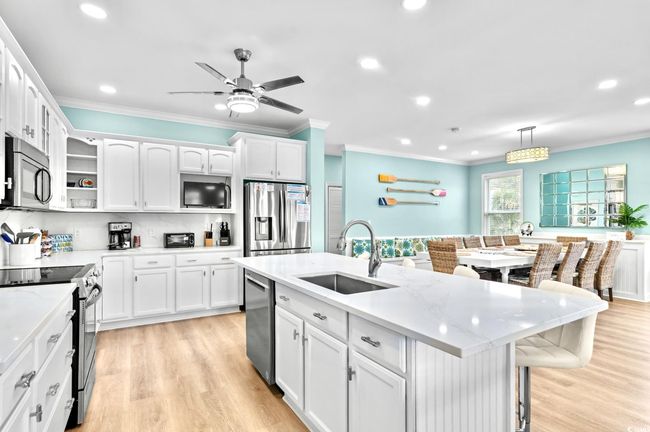Kitchen featuring stainless steel appliances, white cabinetry, a sink, and crown molding | Image 8